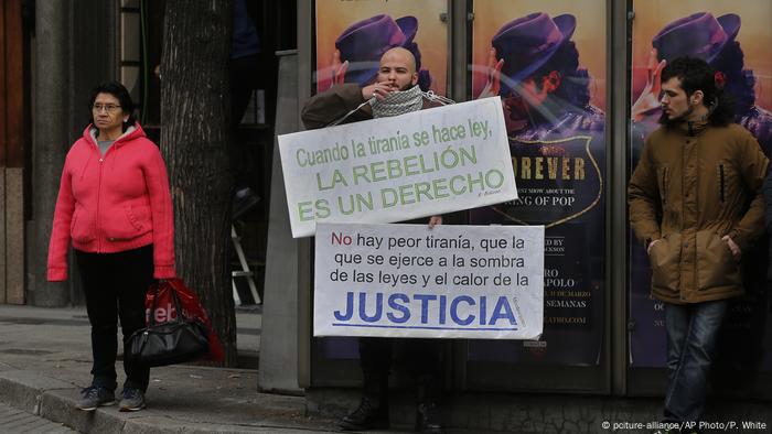 a woman and two men with posters in front of the courthouse 