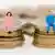 Dois bonecos em miniatura de uma mulher e um homem sentados numa pilha de moedas de euro