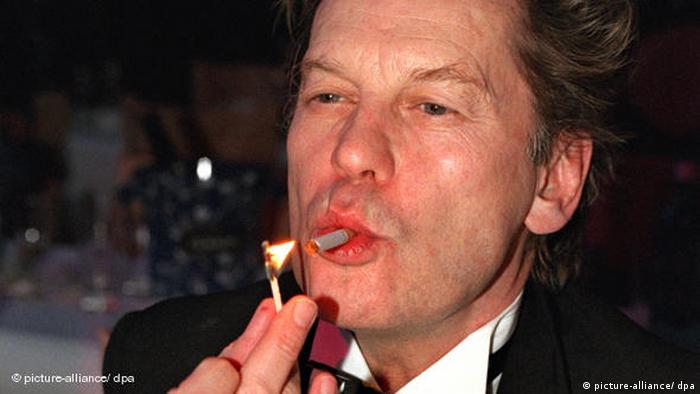 Der Schauspieler Helmut Berger zündet sich eine Zigarette mit einem Streichholz an (Foto: dpa)