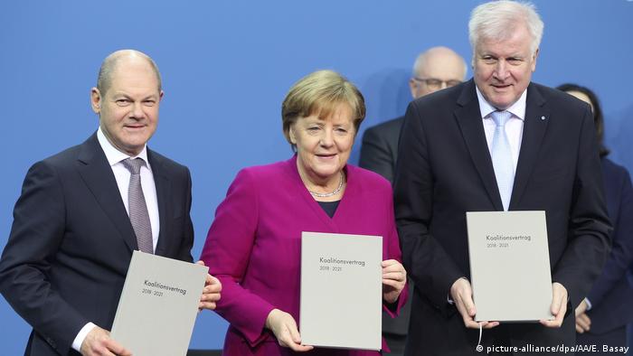 Олаф Шольц (ліворуч), Анґела Меркель (у центрі) та Горст Зеегофер з примірниками підписаної коаліційної угоди