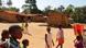 Children stand in a dusty square with mud-brick houses behind them Children stand in a dusty square with mud-brick houses behind them