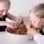 Двоє дітей їдять руками спагетті