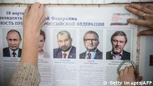 Members of a local election commission install a poster displaying presidential candidates during the preparation of a polling station ahead of Russia's presidential election, on March 17, 2018 in Simferopol, Crimea.
Russians will vote on March 18, a presidential election in which Russian President Vladimir Putin is seeking a fourth term. / AFP PHOTO / STRINGER (Photo credit should read STRINGER/AFP/Getty Images)