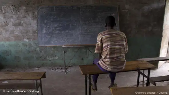 Un élève devant un tableau noir, dans une salle de classe vide (illustration)