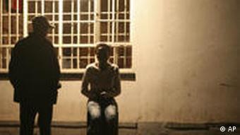 Schatten eines stehenden Mannes und eines auf einem sitzenden Mädchen vor beleuteter Hauswand (Foto: AP)