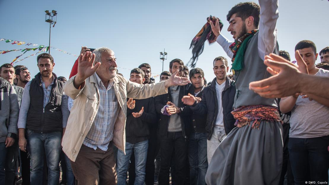 Karşılıklı dans eden iki erkek, etraflarında kalabalık