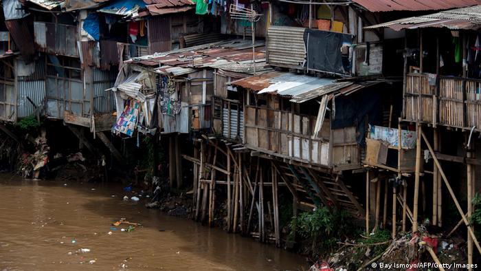 Туалеты позади трущоб, стоящих на сваях у канала в Джакарте.