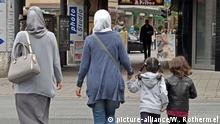 Zwei junge muslimische Frauen gehen mit zwei kleinen Mädchen durch die Fussgängerzone in Bremen.Foto: Winfried Rothermel | Verwendung weltweit