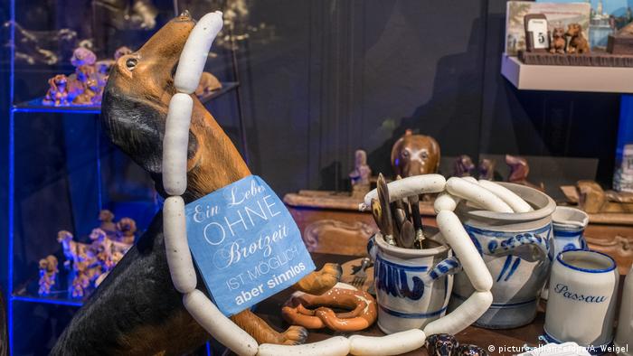 A dog statue holds white veal sausage in its mouth while sitting on a table with soft pretzels at its feet (picture-alliance/dpa/A. Weigel)