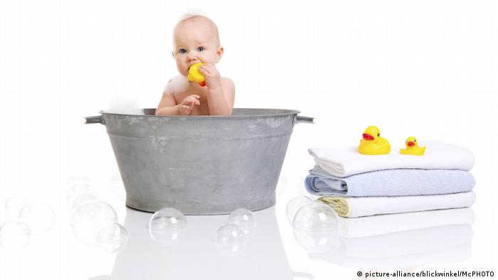 Baby sitting in zinc basin with yellow duck