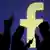 Symbolbild Smartphone-Nutzer vor Facebook Logo