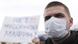 Protester wearing a breathing mask with a placard barely visible in the background Protester wearing a breathing mask with a placard barely visible in the background
