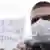 Protester wearing a breathing mask with a placard barely visible in the background