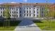 A university building stands next to two lawns in the shade A university building stands next to two lawns in the shade
