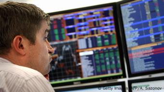 A man on the background of a scoreboard with stock indices 