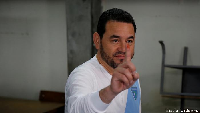 Guatemalan President Jimmy Morales holds up a ink-stained finger from voting