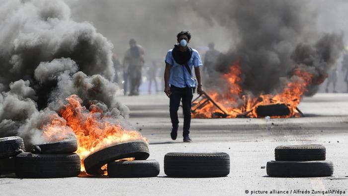 A protester walks between flaming tires