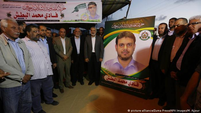 Palestinians gather around a large poster of Fadi al-Batsh during a memorial service in Gaza.