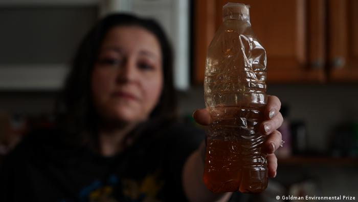 LeeAnne Walters holds plastic bottle with brown polluted water