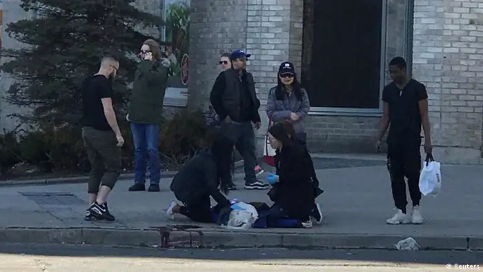 Pedestrians help a victim in Toronto (Reuters)
