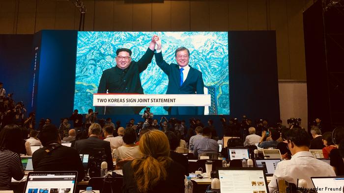 People watching Kim and Moon on TV (DW/Alexander Freund)