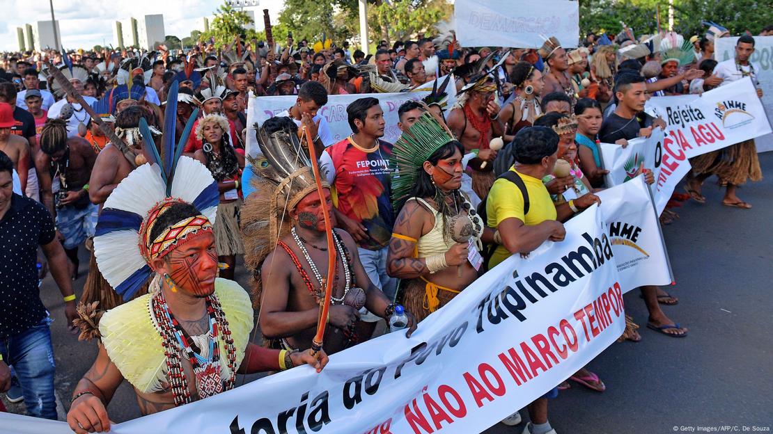 Indígenas com cocares seguram uma faixa contra o marco temporal