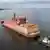 A barge containing two nuclear reactors is towed out to sea by at least three tug boats from its port in St. Petersburg.