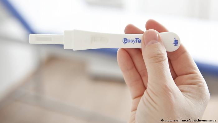 A hand holds a pregnancy test