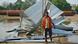 A man standing in front of a collapsed hut A man standing in front of a collapsed hut