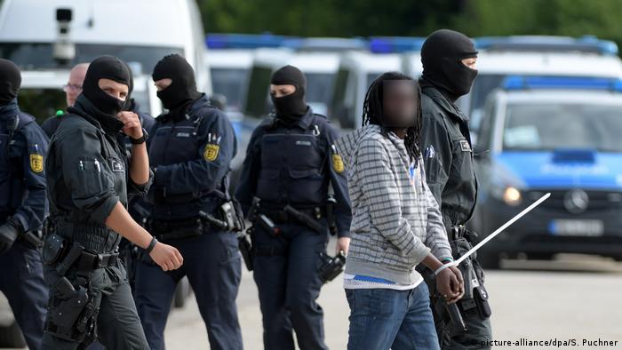 Police escort an asylum-seeker away