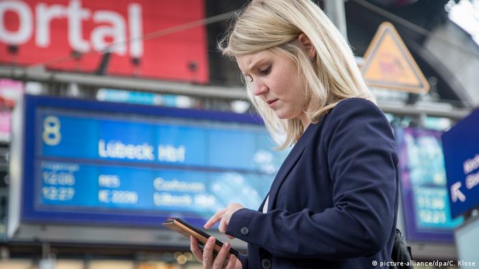 Жінка дивиться в мобільний телефон на вокзалі 