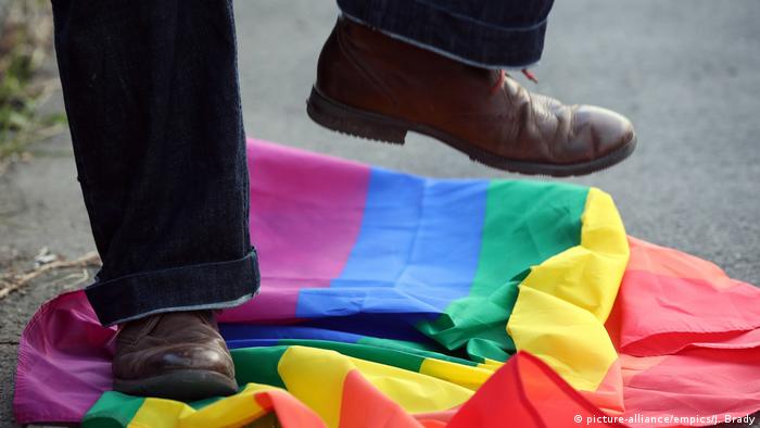 A person stamping on an LGBT pride flag