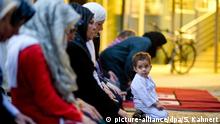Hamsa (2) kniet am 25.07.2013 in Hannover (Niedersachsen) im Rahmen der Langen Nacht der Begegnung während des Abendgebets vor muslimischen Frauen auf einem Gebetsteppich. Im Ramadan folgt das Abendgebet dem Fastenbrechen nach Einbruch der Dunkelheit. Foto: Sebastian Kahnert/dpa +++(c) dpa - Bildfunk+++ |