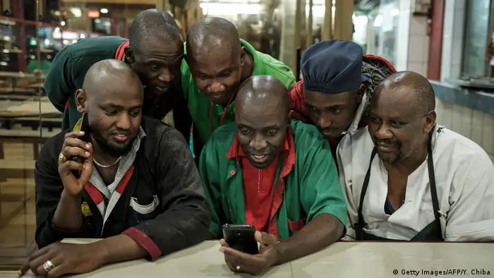 Several men look at a phone screen