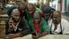 Several men look at a phone screen