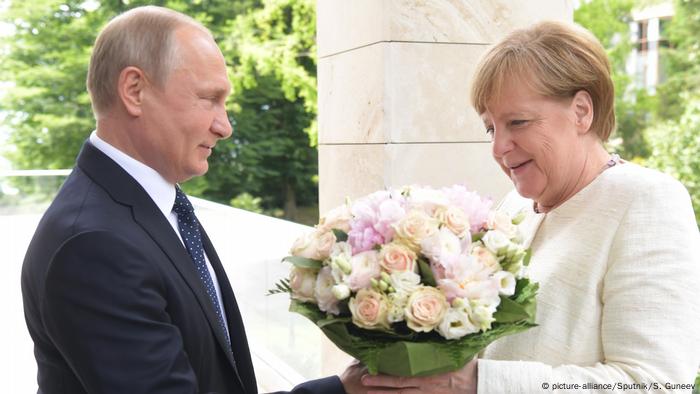 Putin gives Merkel a bouquet of flowers in Sochi, May 2018