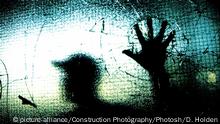Der Schatten einer Person hinter einer gesprungenen Scheibe (Quelle: picture-alliance/Construction Photography/Photosh/D. Holden)