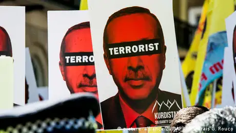 Kurdish protesters hold up a sign calling Erdogan a terrorist