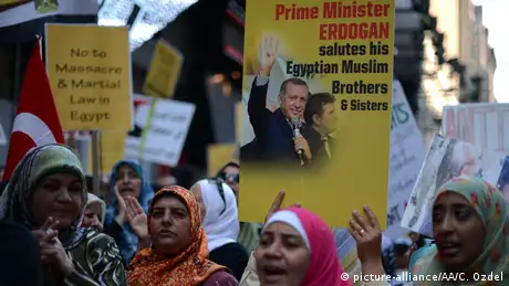 Protesters carry signs of Erdogan claiming to support the Muslim Brotherhood