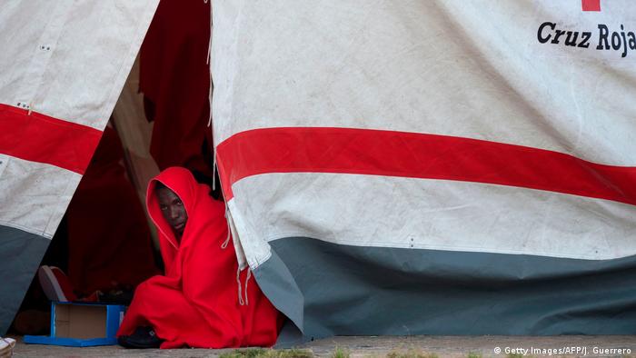 A migrant keeps warm inside a Red Cross tent upon his arrival at Malaga's harbour on April 26, 2018