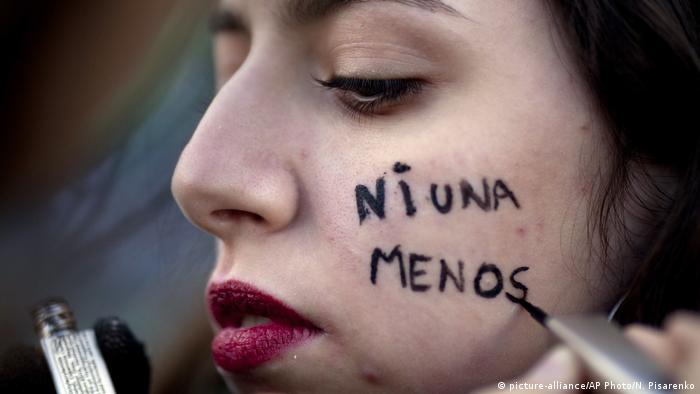 A woman has 'Ni Una Menos' painted on her chee