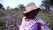 A woman in rural Uganda wearing a straw hat smiles and looks off to the side A woman in rural Uganda wearing a straw hat smiles and looks off to the side