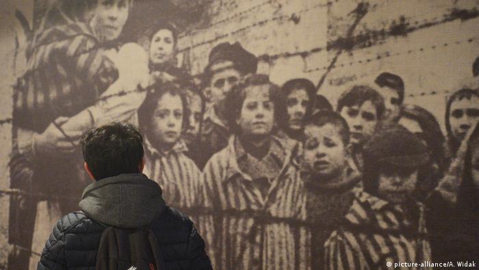 Ein Foto von Kindern in KZ-Kleidung hinter Stacheldraht. (picture-alliance/A. Widak)