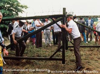 Österreichische Grenzbeamte öffnen ein Grenztor. Hunderte DDR-Bürger nutzten ein paneuropäisches Picknick an der ungarisch-österreichischen Grenze, bei dem ein Grenztor symbolisch geöffnet wurde, zur Flucht in den Westen. (Foto: dpa)