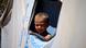 A Syrian kid looks out from a tent's window A Syrian kid looks out from a tent's window
