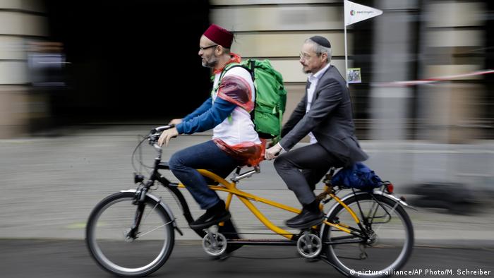 A Muslim man and a Jewish man ride a tandem bicycle in Berlin in a demonstration against religious discrimination