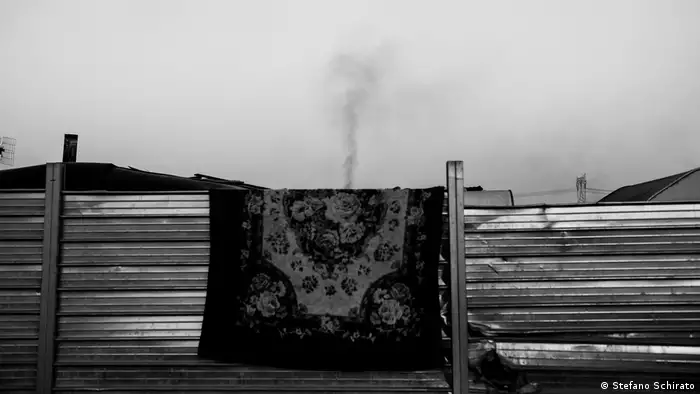 A rug hanging over a fence with smoke rising above it (Stefano Schirato)