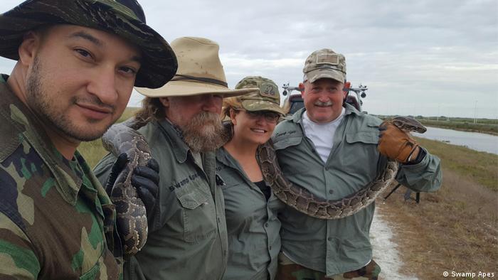 A group of people hold a snake