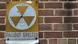 A sign for a nuclear fallout shelter on a brick wall A sign for a nuclear fallout shelter on a brick wall