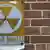 A sign for a nuclear fallout shelter on a brick wall